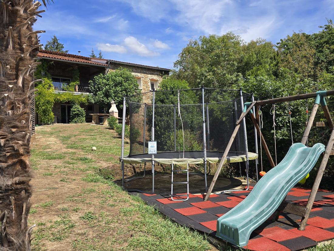 Cama elástica, tobogán y columpios en la finca, frente a la casa