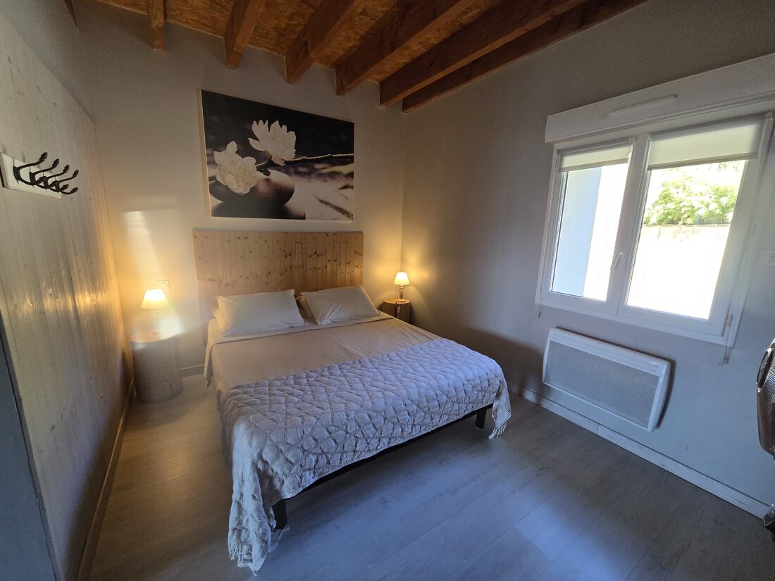 Chambre avec lit double, tête de lit en bois et poutres apparentes